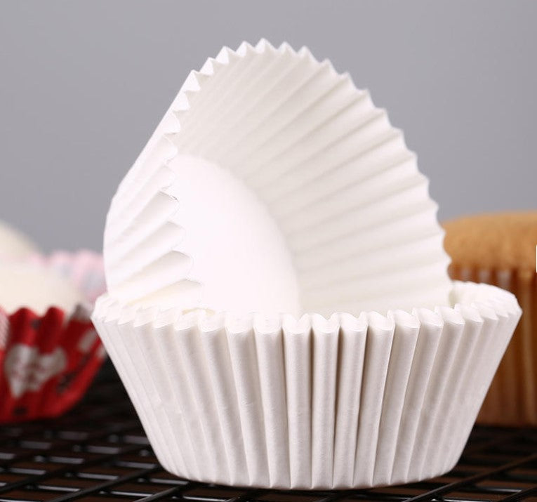 White paper cupcake liners on a cooling rack with a gray background