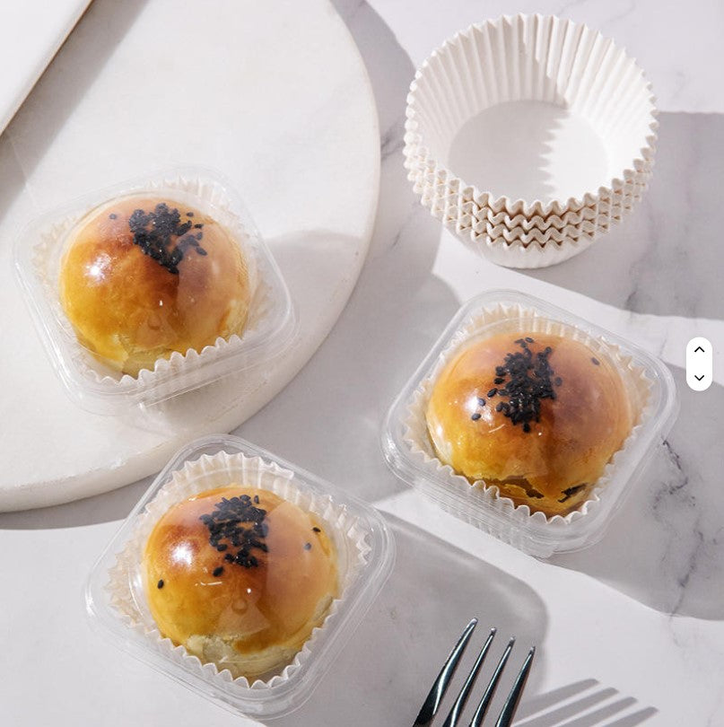 Three pastries in clear containers on a marble surface with a fork beside them.