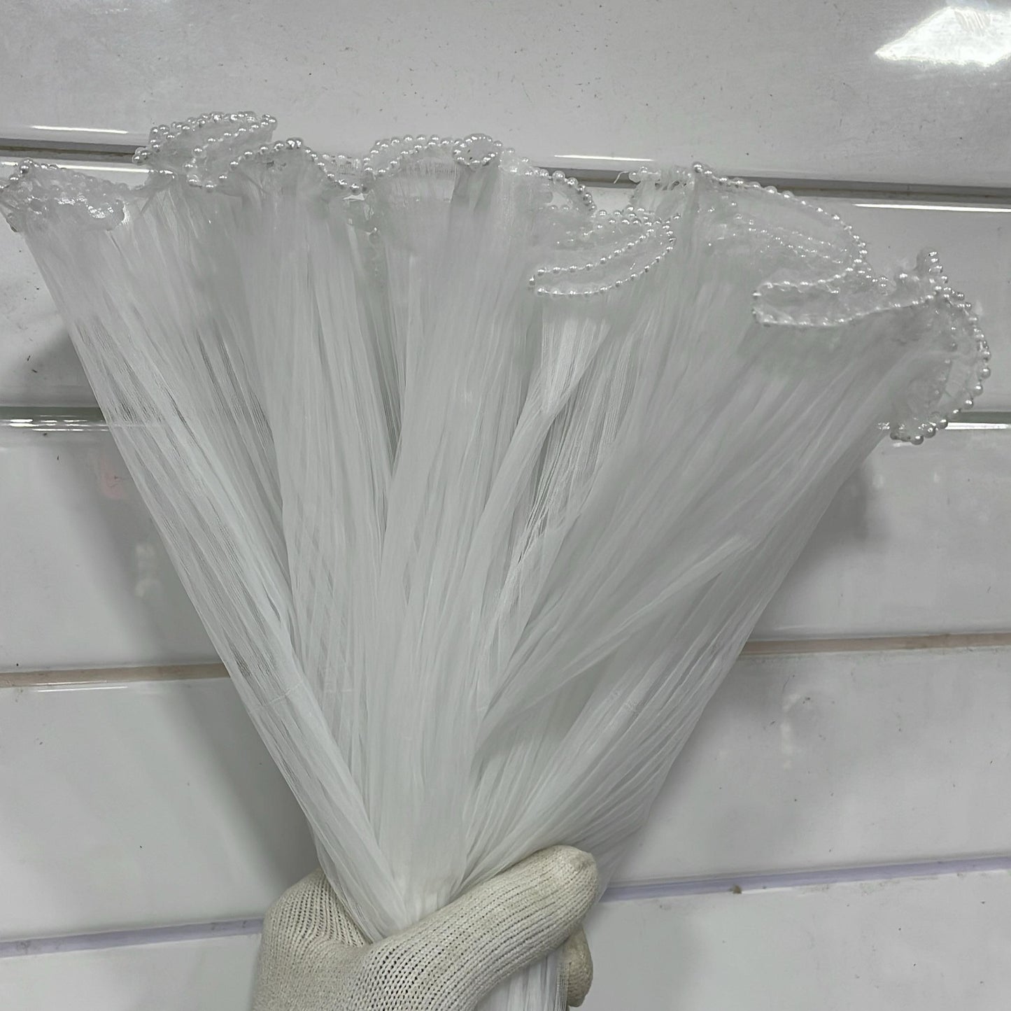 Hand holding a bundle of clear plastic straws against a white background