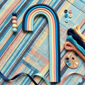 Colorful rainbow-shaped clay on a textured fabric background with buttons and yarn.