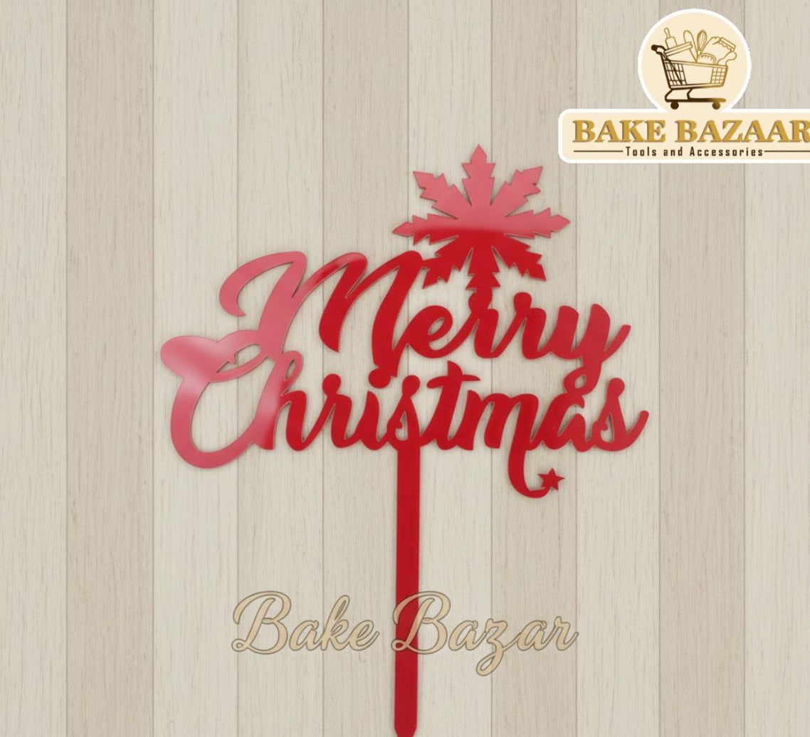 Red 'Merry Christmas' cake topper with palm tree design on a wooden background, branded 'Bake Bazaar'.