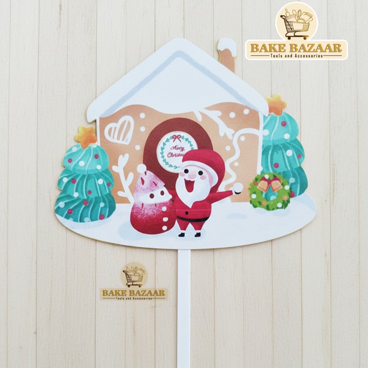 Decorative standee of a gingerbread house with Santa Claus on a wooden background, branded 'Bake Bazaar'.
