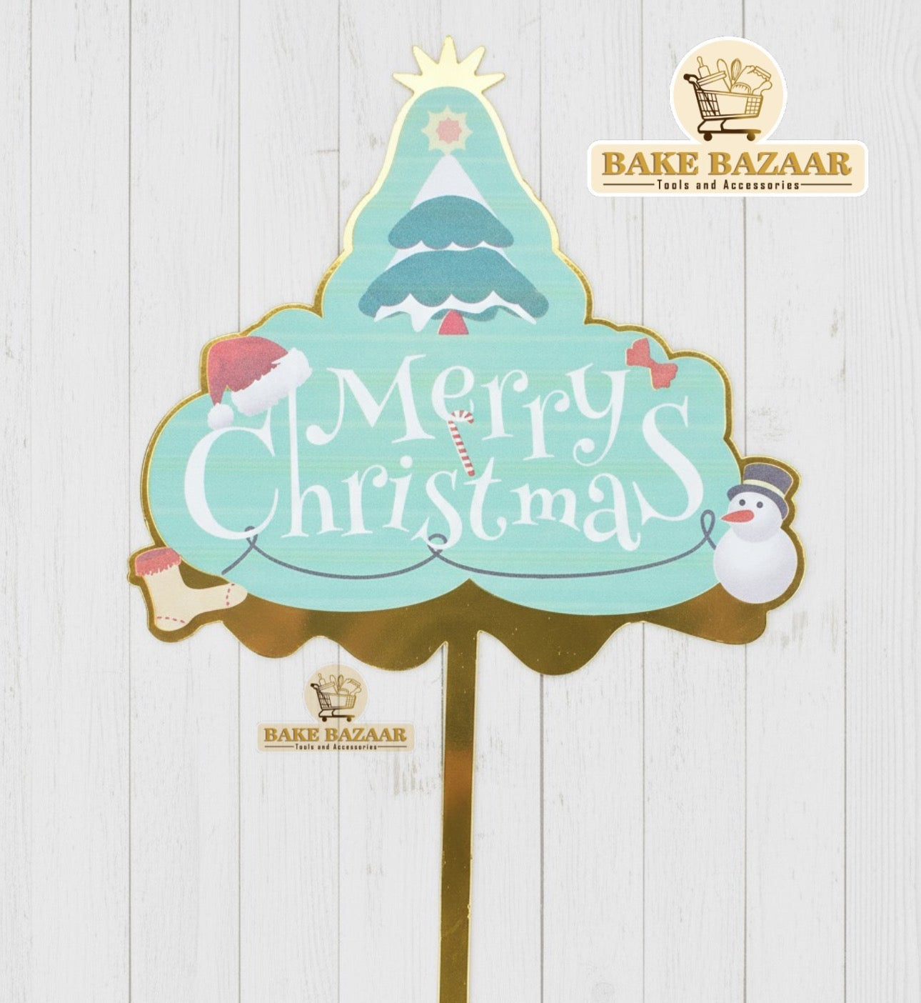 Decorative Christmas sign with 'Merry Christmas' text on a white wooden background, featuring Bake Bazaar branding.