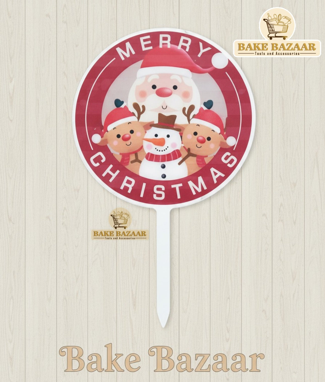 Christmas-themed cake topper with Santa Claus and reindeer on a wooden surface, branded 'Bake Bazaar'.