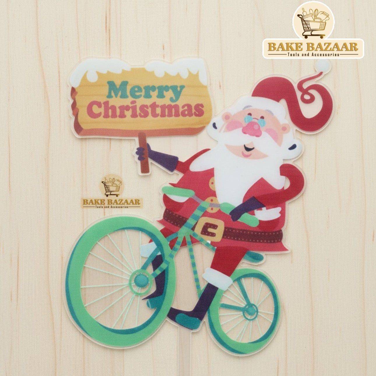 Decorative sign with Santa Claus on a bike and 'Merry Christmas' text, branded 'Bake Bazaar'.