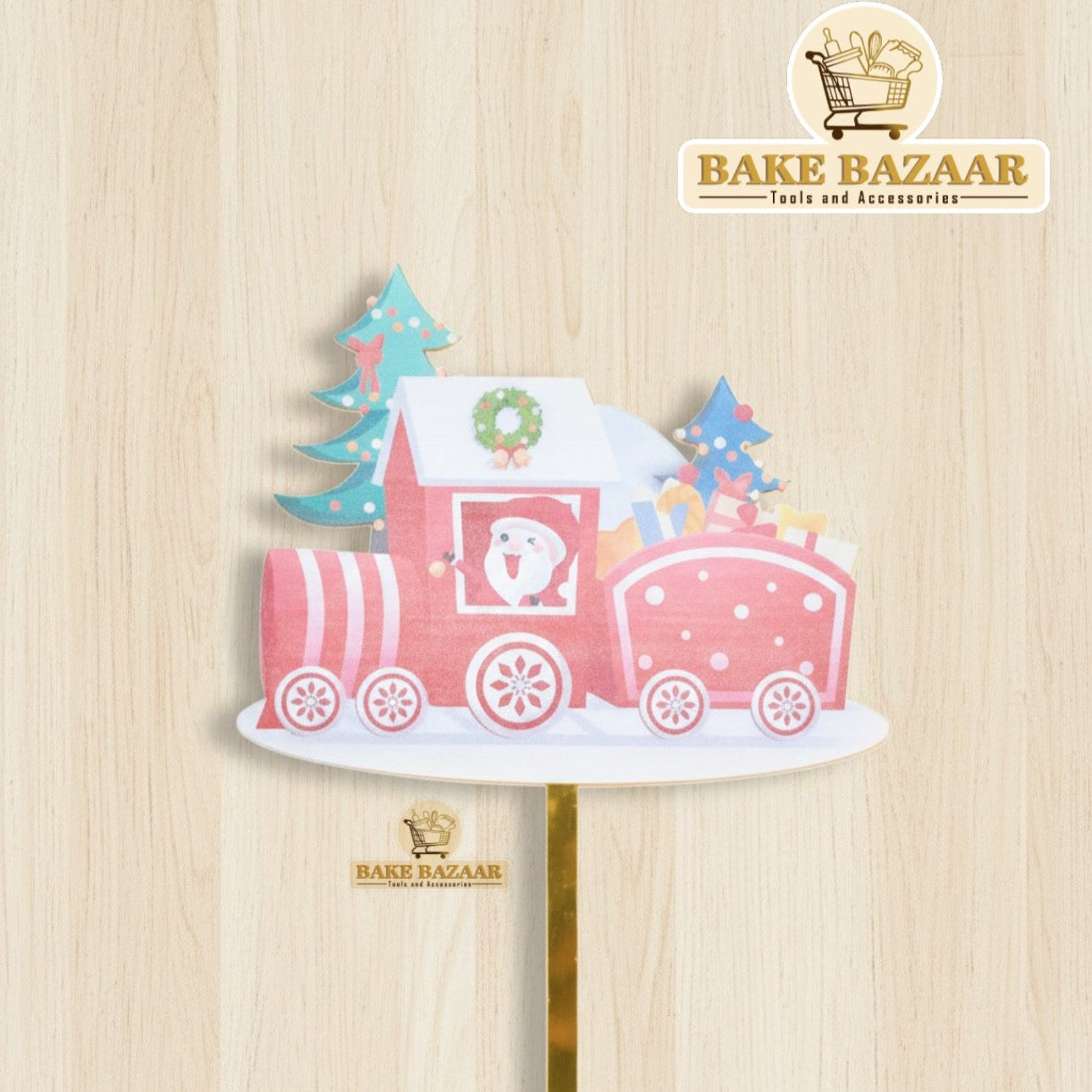 Decorative cake topper with a pink train design on a wooden background, branded 'Bake Bazaar'.
