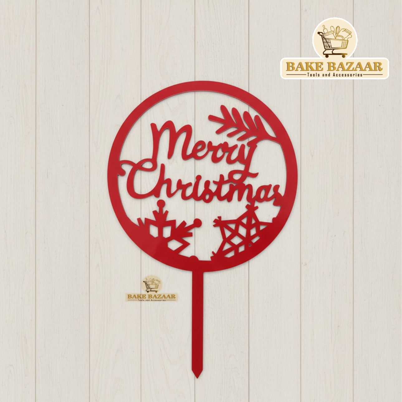 Red 'Merry Christmas' cake topper with Bake Bazaar branding on a light wooden background