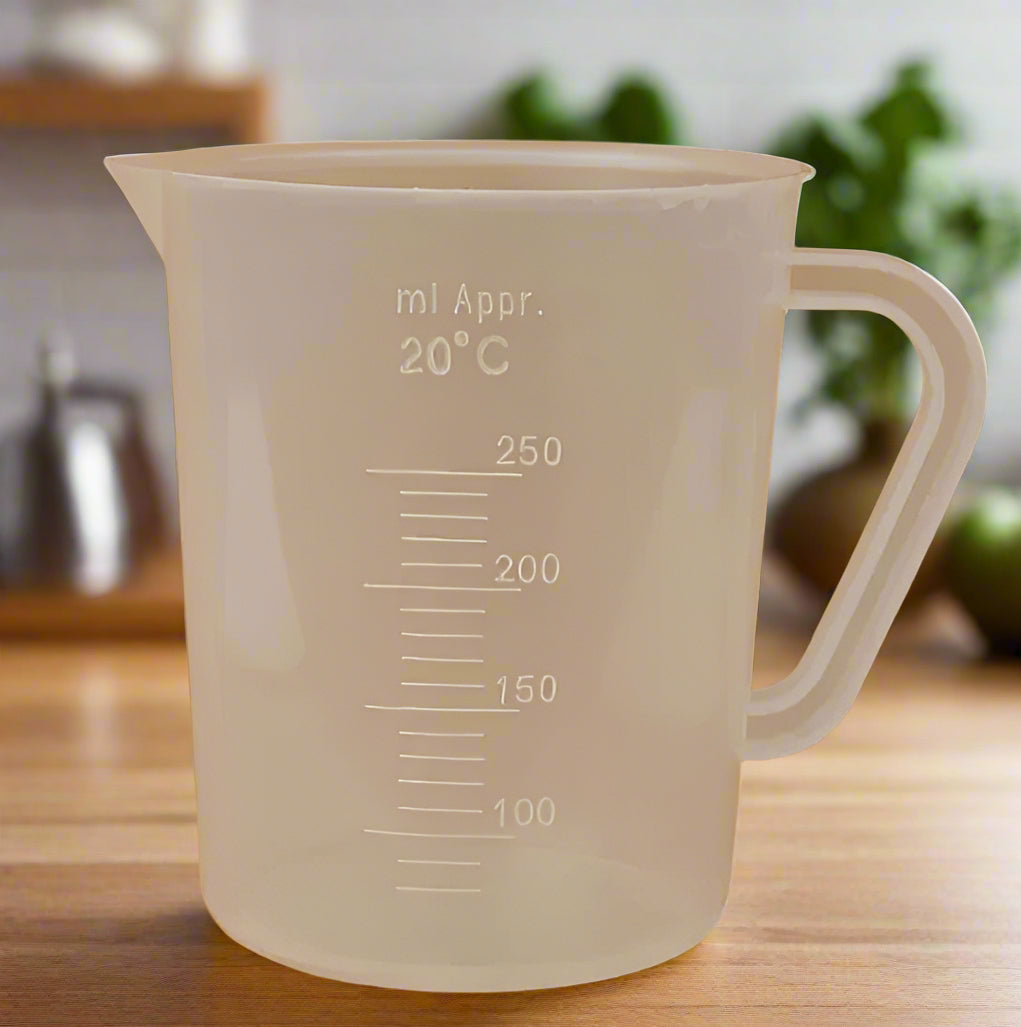 Clear plastic measuring cup with measurement markings on a brown background