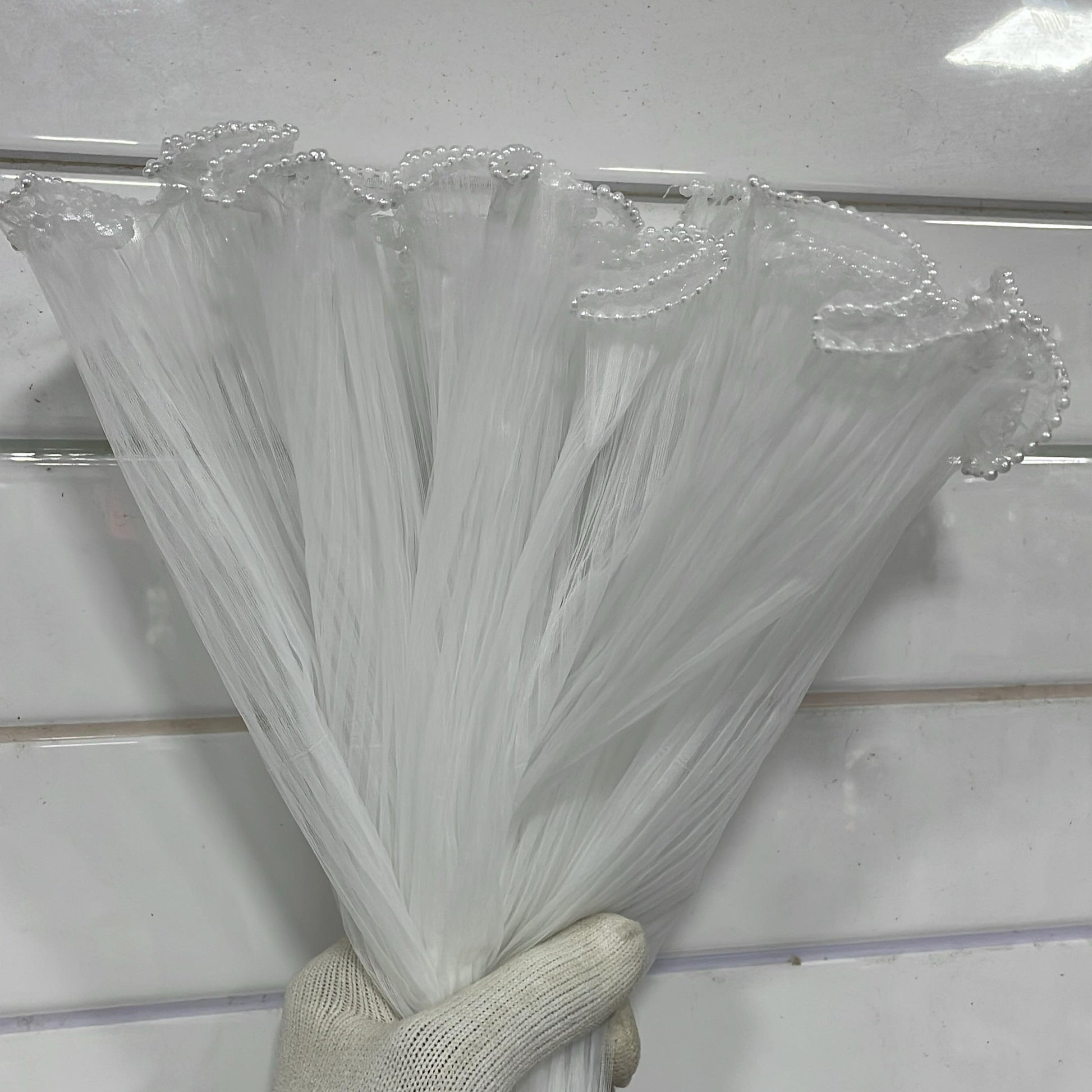 Hand holding a bundle of clear plastic straws against a white background